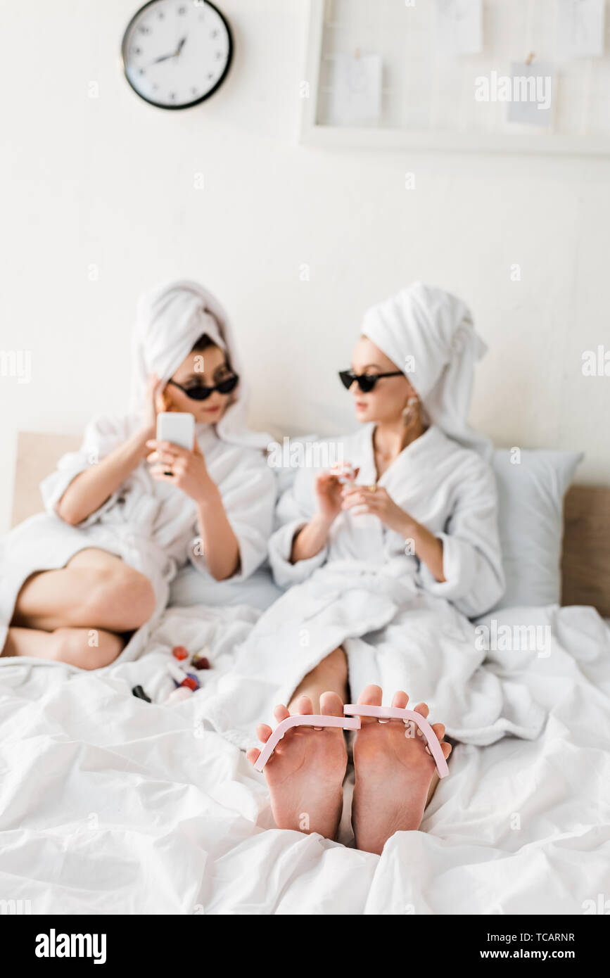 selective focus of barefoot woman in bathrobe and sunglasses lying with  pedicure in bed Stock Photo - Alamy