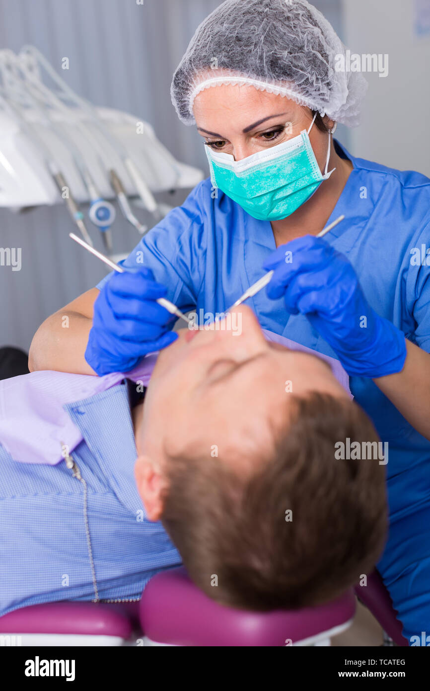 dentist professional filling teeth for man patient sitting in medical
