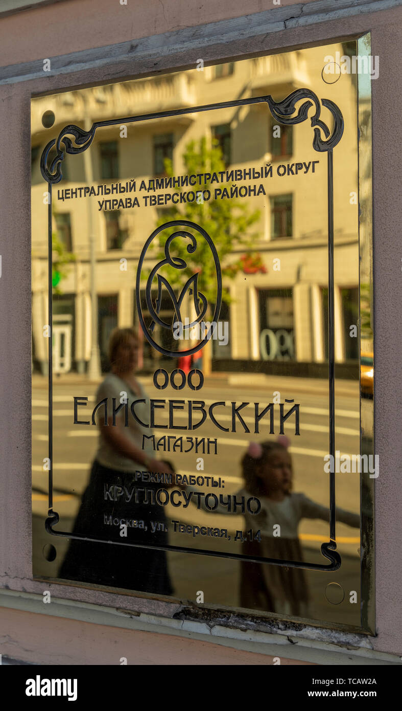 Woman and girl reflected in the brass plaque of the famed Eliseevsky Gastronom #1 food store at Tverskaya 14, Moscow Russia Stock Photo