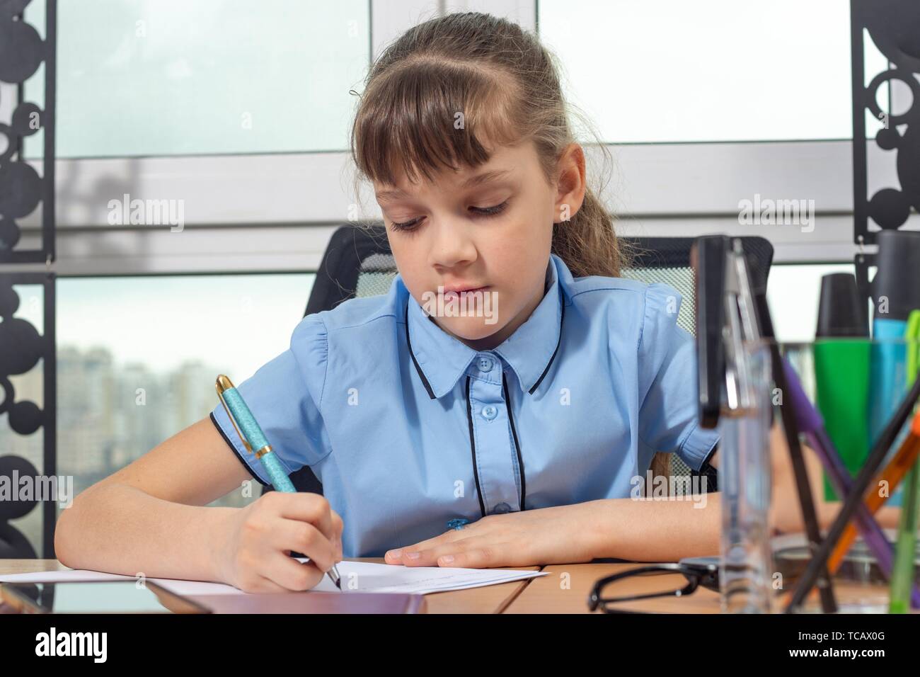 A girl of eight years old is concentrating writing with a fountain pen