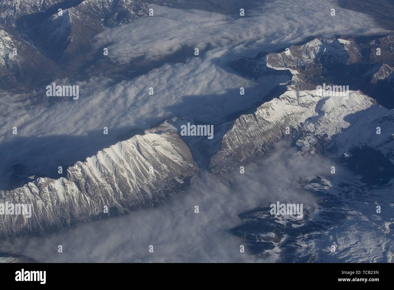 Swiss Alpes with snowy mountain tops aerial view towards the east during afternoon flight in December. Stock Photo