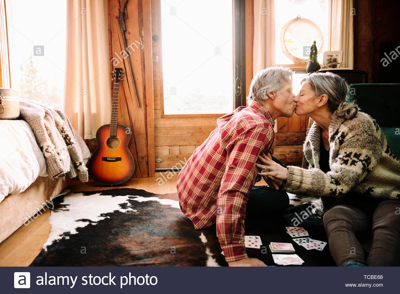 Affectionate mature couple playing cards, kissing in cabin Stock Photo