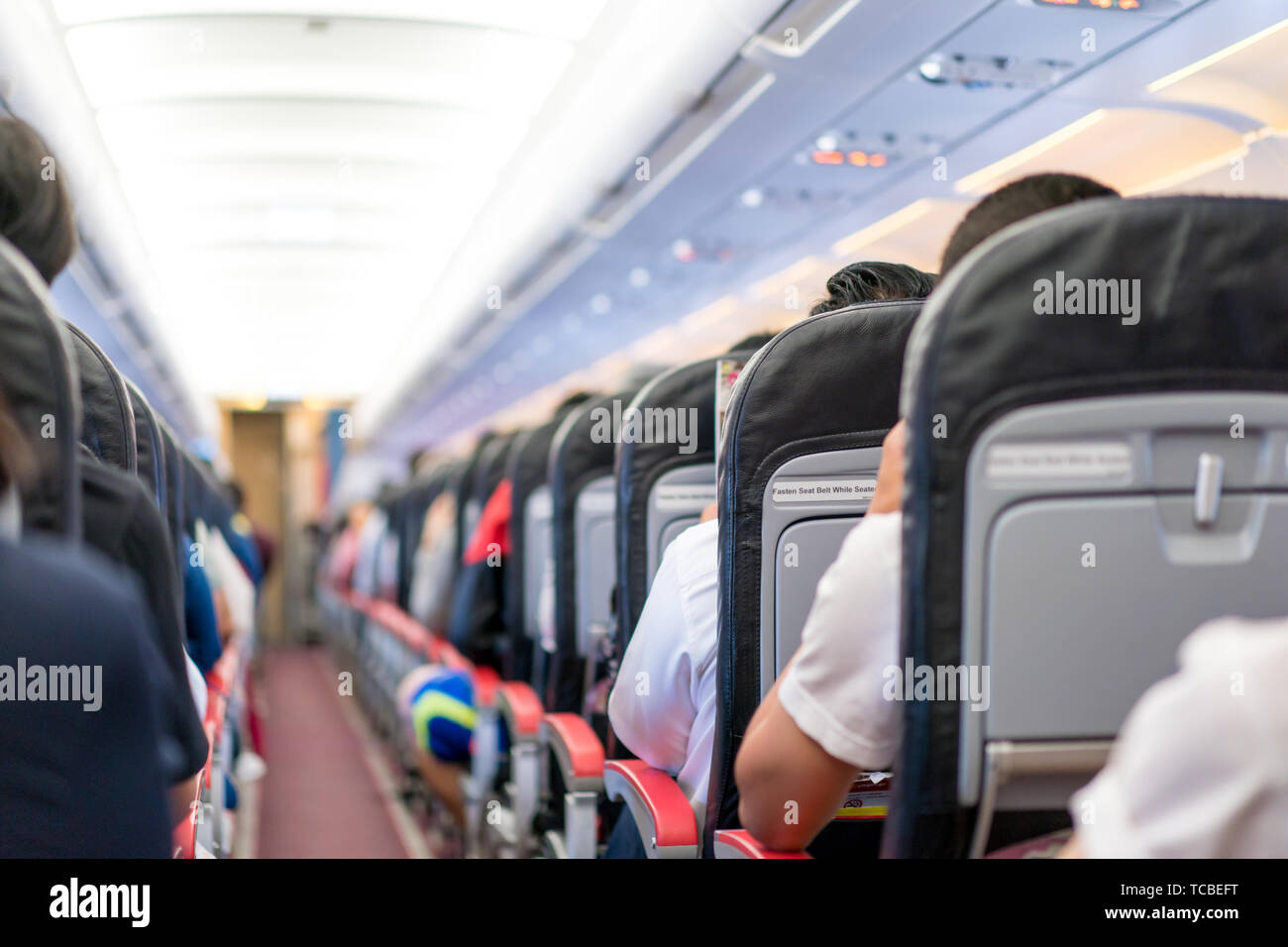 Asian passenger reading the magazine / menue / catalog while waiting for plane take of inflight. Stock Photo