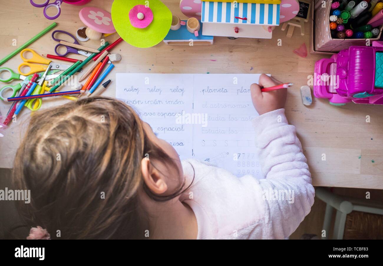 6 years old child girl doing writing homework in her room. Kids learn to write concept. Stock Photo