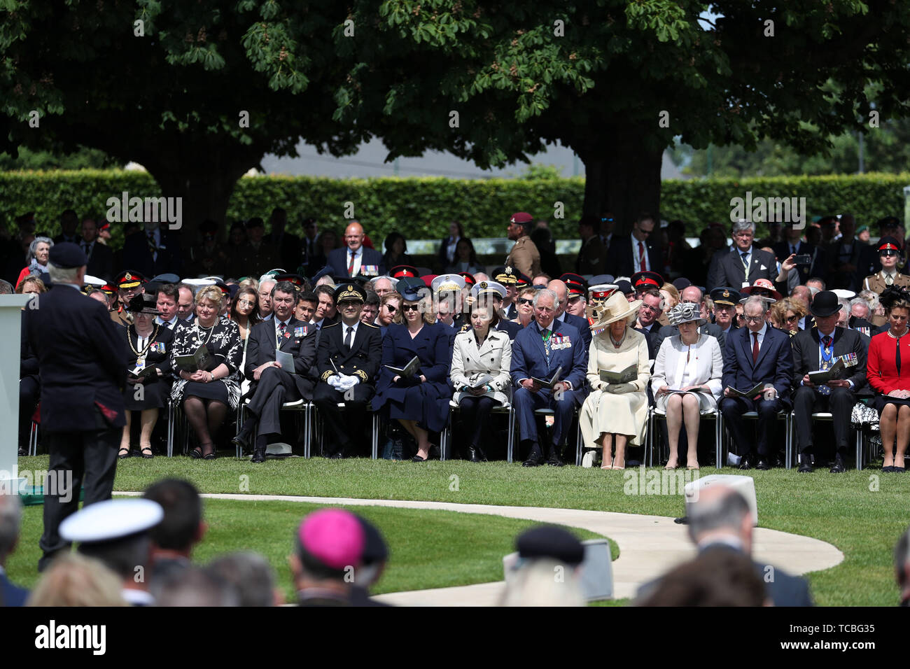 The Prince of Wales and the Duchess of Cornwall listen to veteran Frank Baugh (left), who served as a signalman with the Royal Navy on a landing craft during D-Day during the Royal British Legion's Service of Remembrance, at the Commonwealth War Graves Commission Cemetery, in Bayeux, France, as part of commemorations for the 75th anniversary of the D-Day landings. Stock Photo
