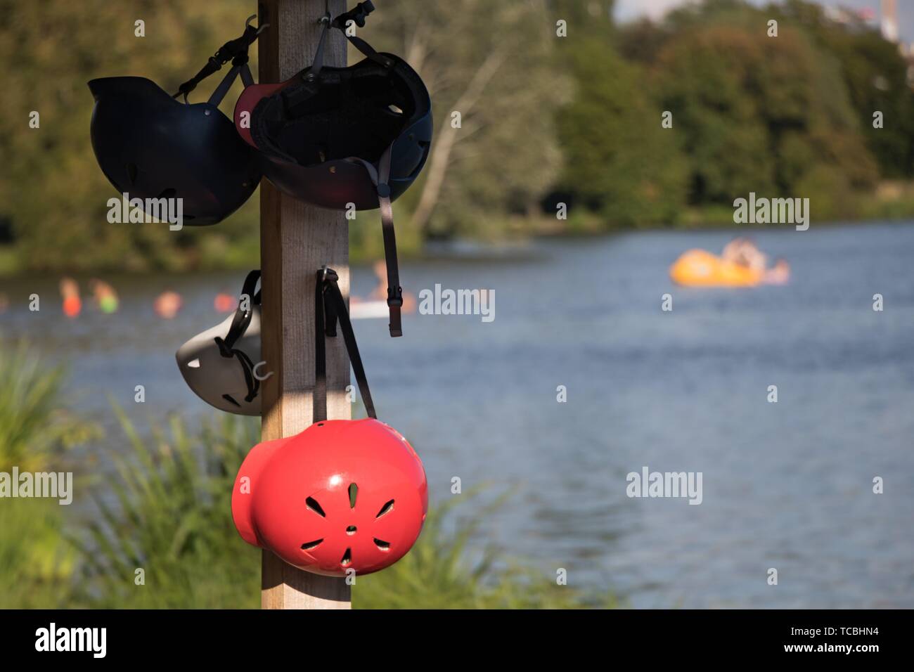 Wakeboard helmets hanging on a pole near the lake. Stock Photo