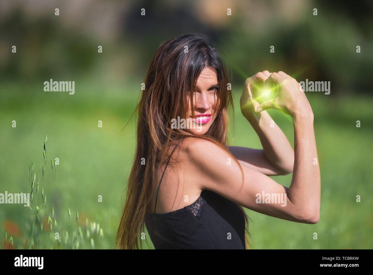 Woman smiling. Heart symbol shaped with green flare inside. Love, nature concept. Ecology and sustainability. Stock Photo