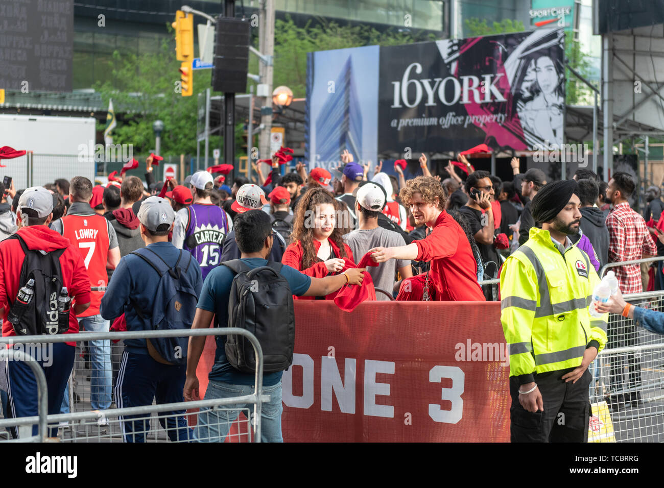 Volunteers handing out red cloths to fans entering the exterior fan areas in Bremner Boulevard. NBA playoffs fever in the Canadian city.It is the Stock Photo