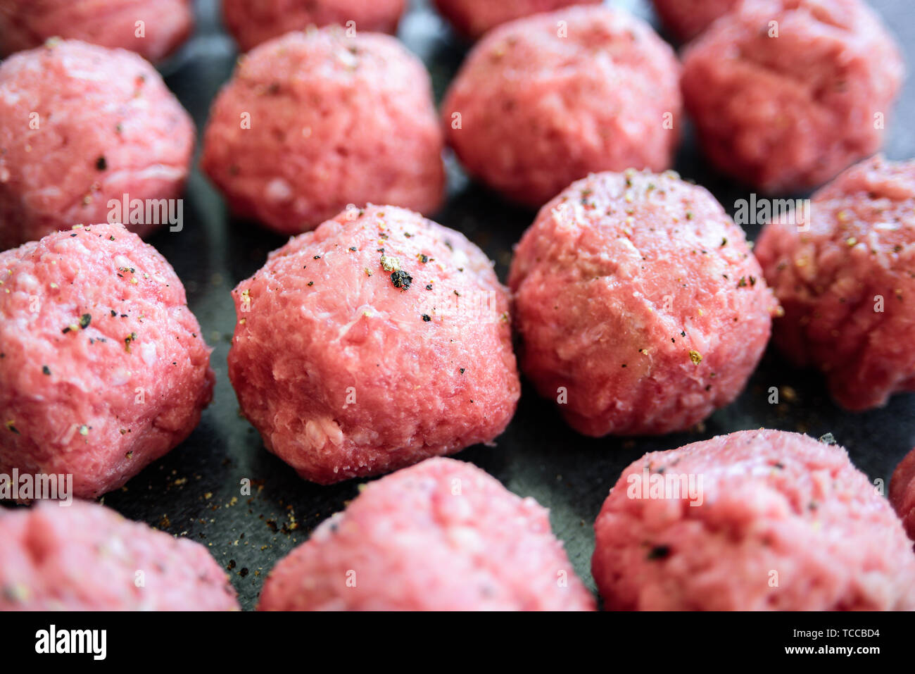 Raw uncooked turkey meatballs on tray. Fresh minced meat, pepper, salt Stock Photo