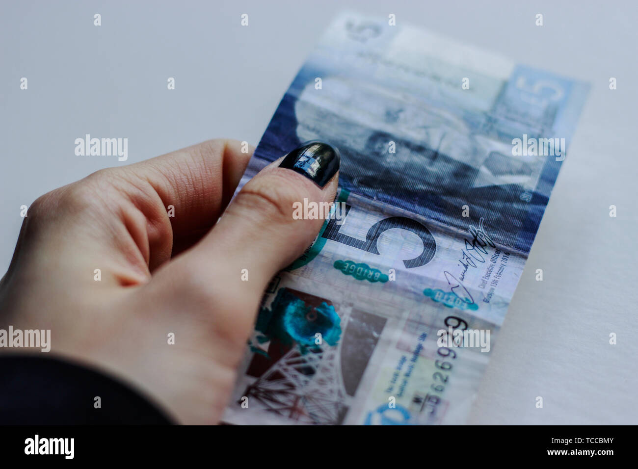 Bank of Scotland £5 note, a fiver, banknote of the pound sterling, May 2019, UK.Woman holding 5 pounds paper Scottish bank note over isolated backgrou Stock Photo