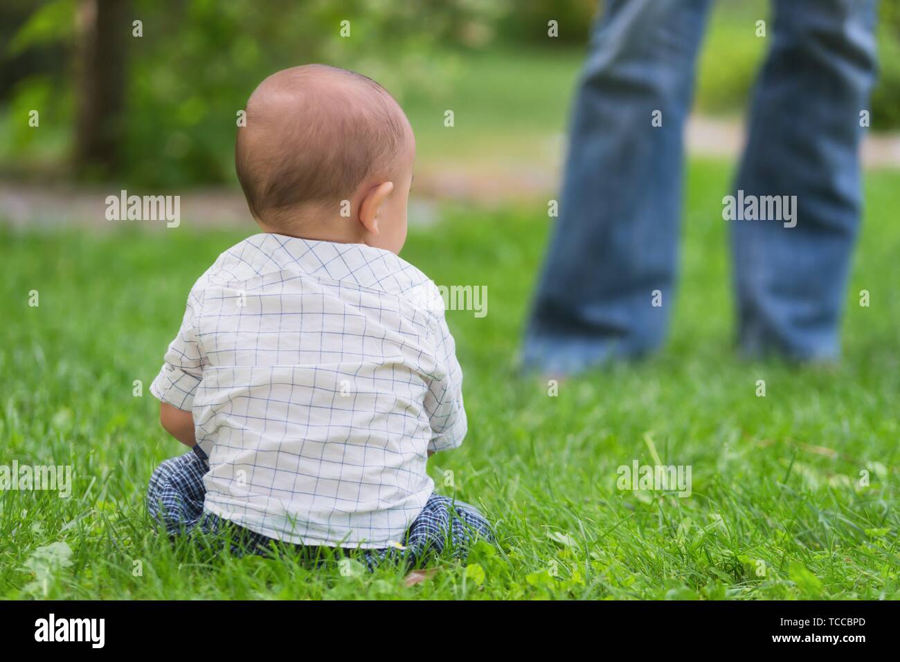 Dangerous situation, baby lost in the park, unknown person approaching. Stock Photo