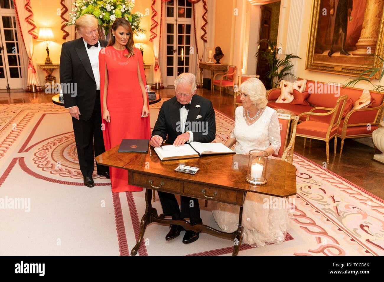 U.S President Donald Trump and First Lady Melania Trump look on as Prince of Wales and the Duchess of Cornwall sign the guestbook during a gala at Winfield House hosted by the Trumps June 4, 2019 in London, England. Stock Photo