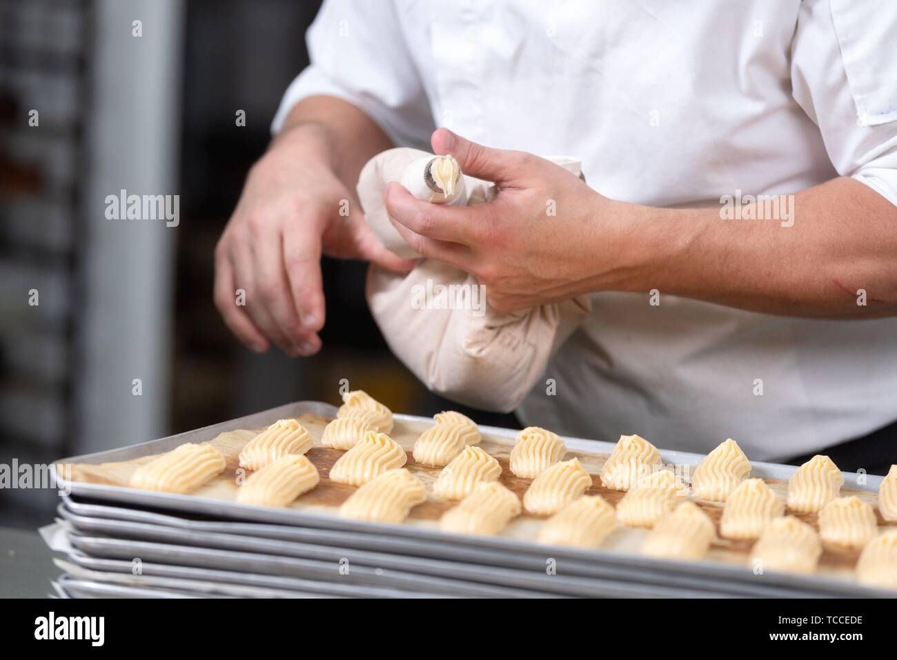 Close up of Pastry Chef with confectionary bag squeezing cream at pastry shop. Stock Photo