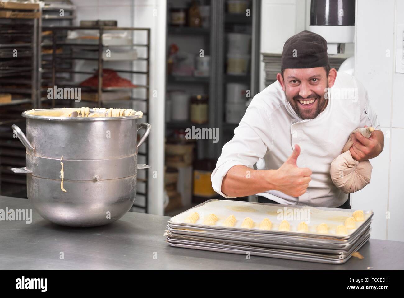 Pastry Chef with confectionary bag squeezing cream at pastry shop. Stock Photo