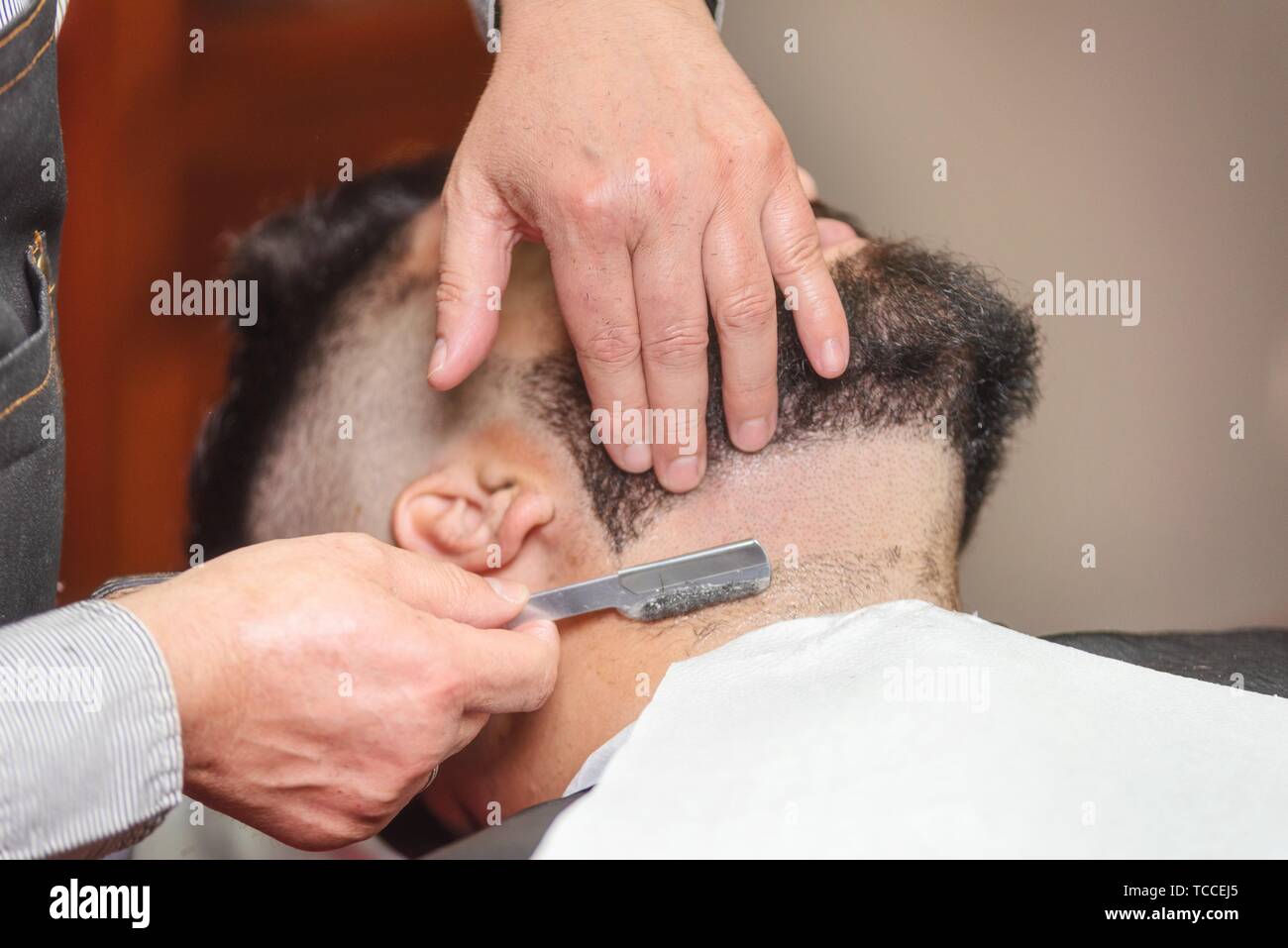 Handsome man having a shave with vintage razor at the barbershop. Stock Photo