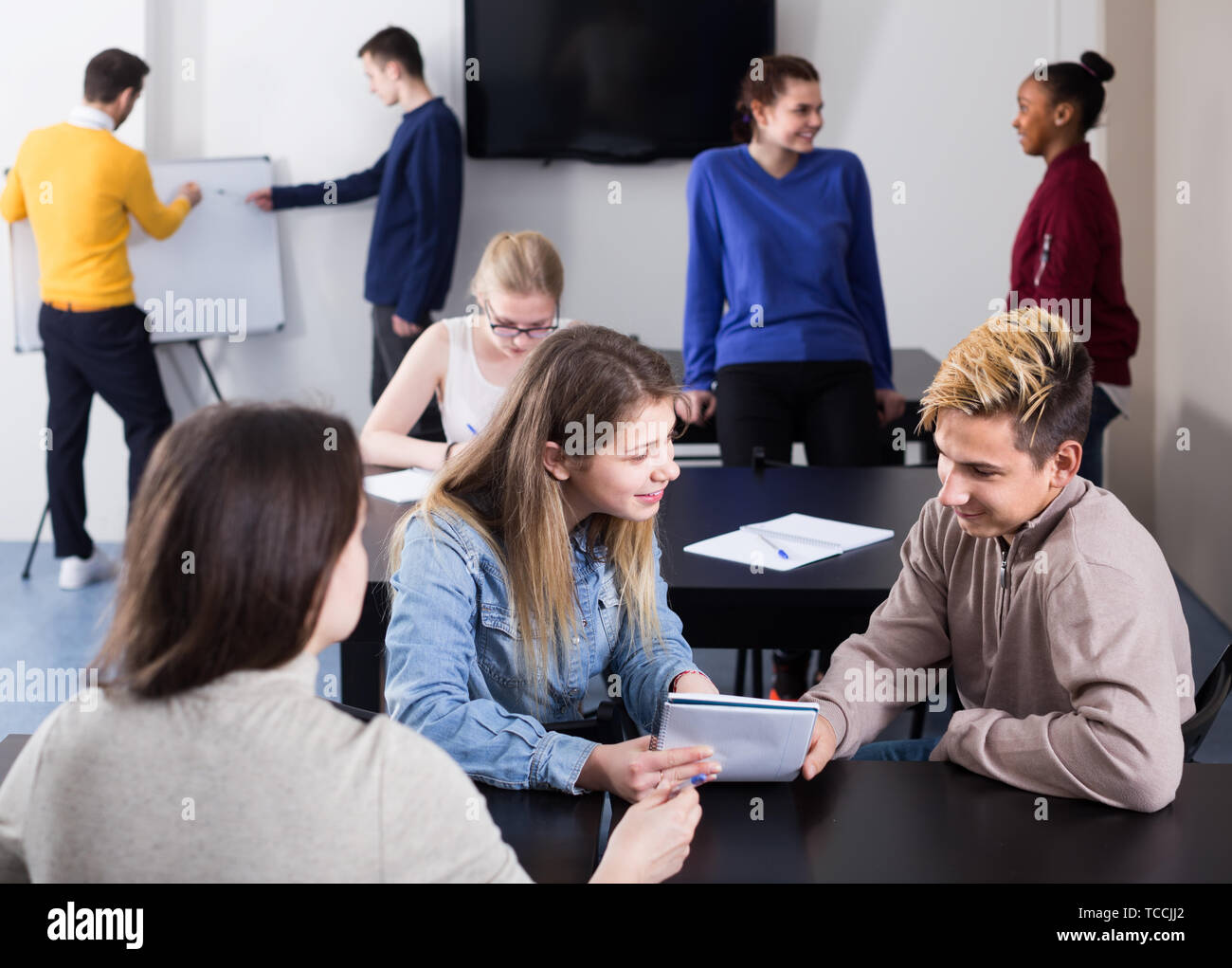 active classmates having animated talks at break between classes sits ...