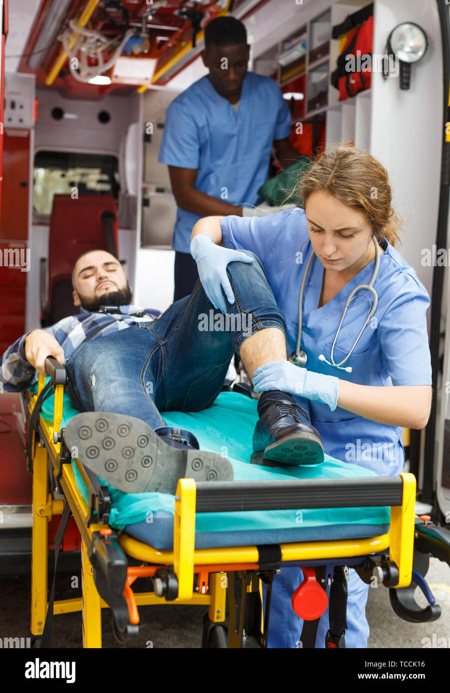 Ambulance team providing medical care to patient on stretcher in ...