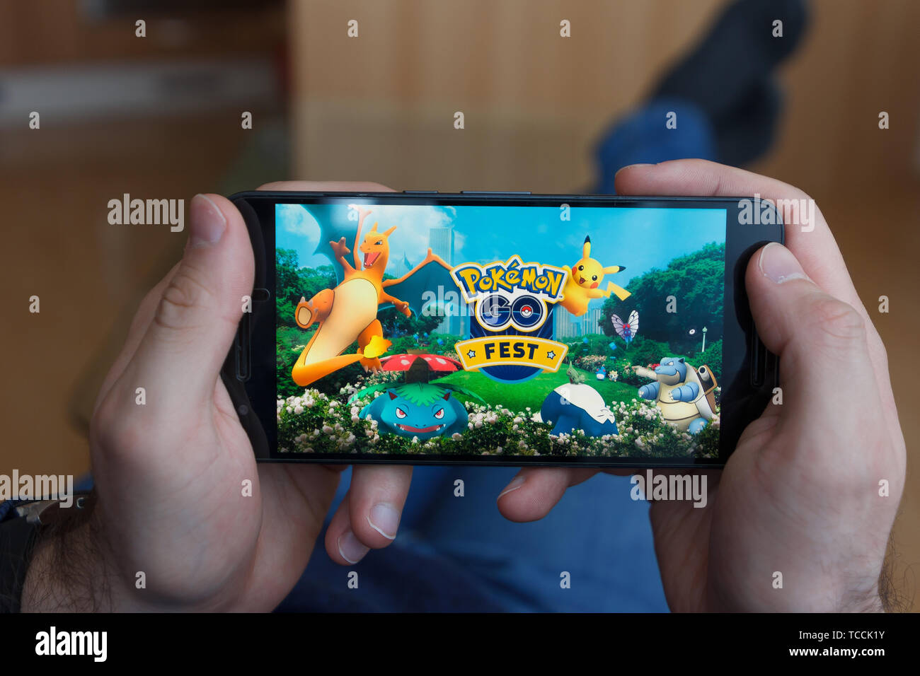 LOS ANGELES, CALIFORNIA - JUNE 3, 2019: Lying Man holding a smartphone and playing the Pokemon Go game on the smartphone screen. An illustrative edito Stock Photo