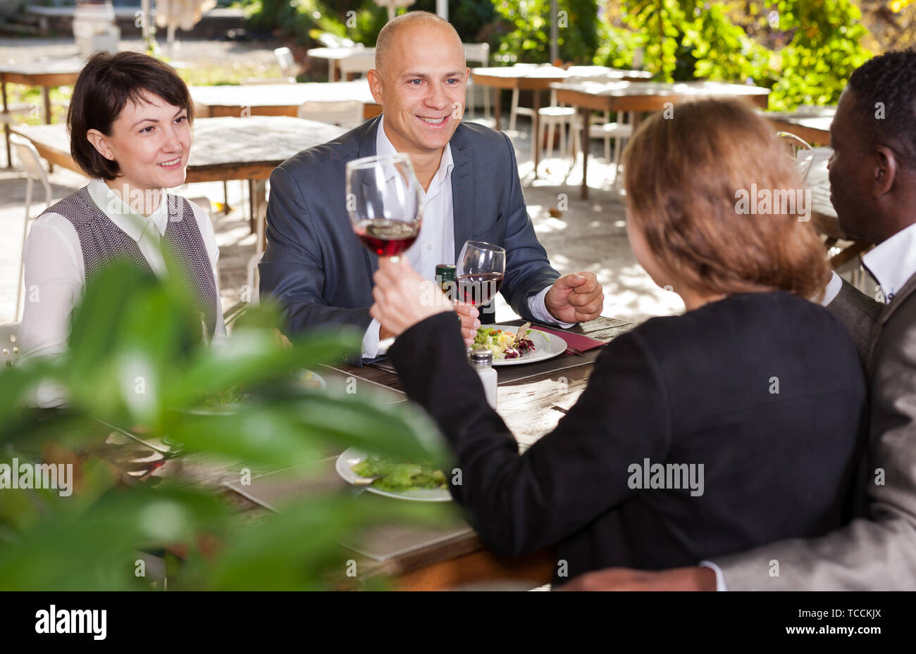 Two happy couples having lunch at open-air restaurant summer Stock Photo