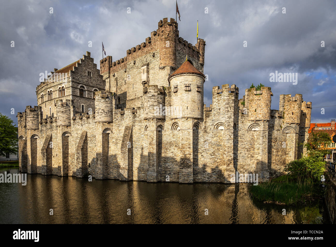Fortified walls and towers of Gravensteen medieval castle with moat in the foreground, Ghent East Flanders, Belgium Stock Photo