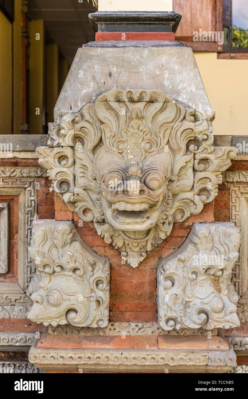 Klungkung, Bali, Indonesia - February 26, 2019: Royal Palace. Closeup of beige mask mural set on red bricks under pillar at entrance museum. Stock Photo