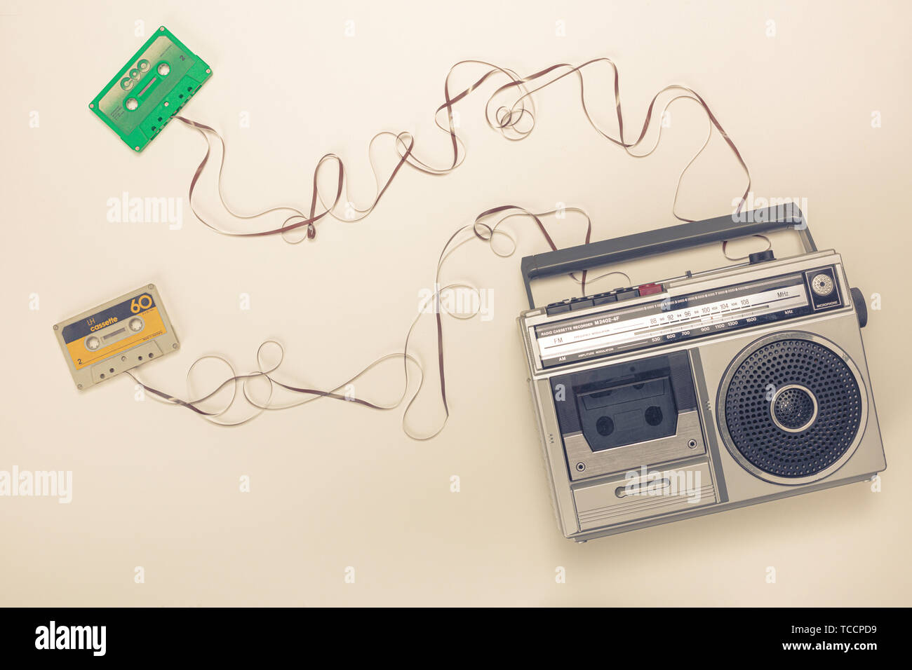 Old radio with tape recorder and cassettes with ribbon forming a wire. Flat lay style. Stock Photo