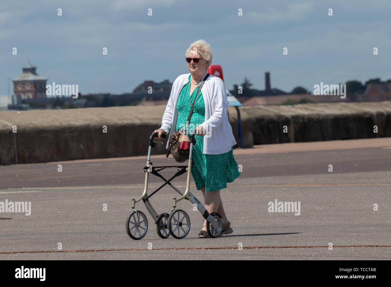 An elderly lady walking with a Zimmer frame or mobility aid Stock Photo