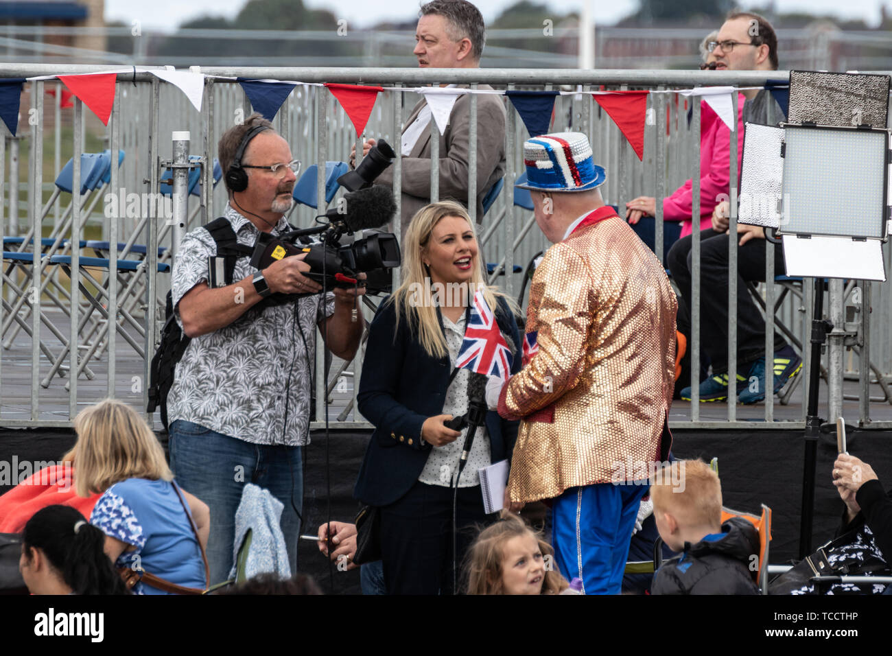 a news reporter and camera man interviewing a man dressed in union jack clothing at a commemoration Stock Photo