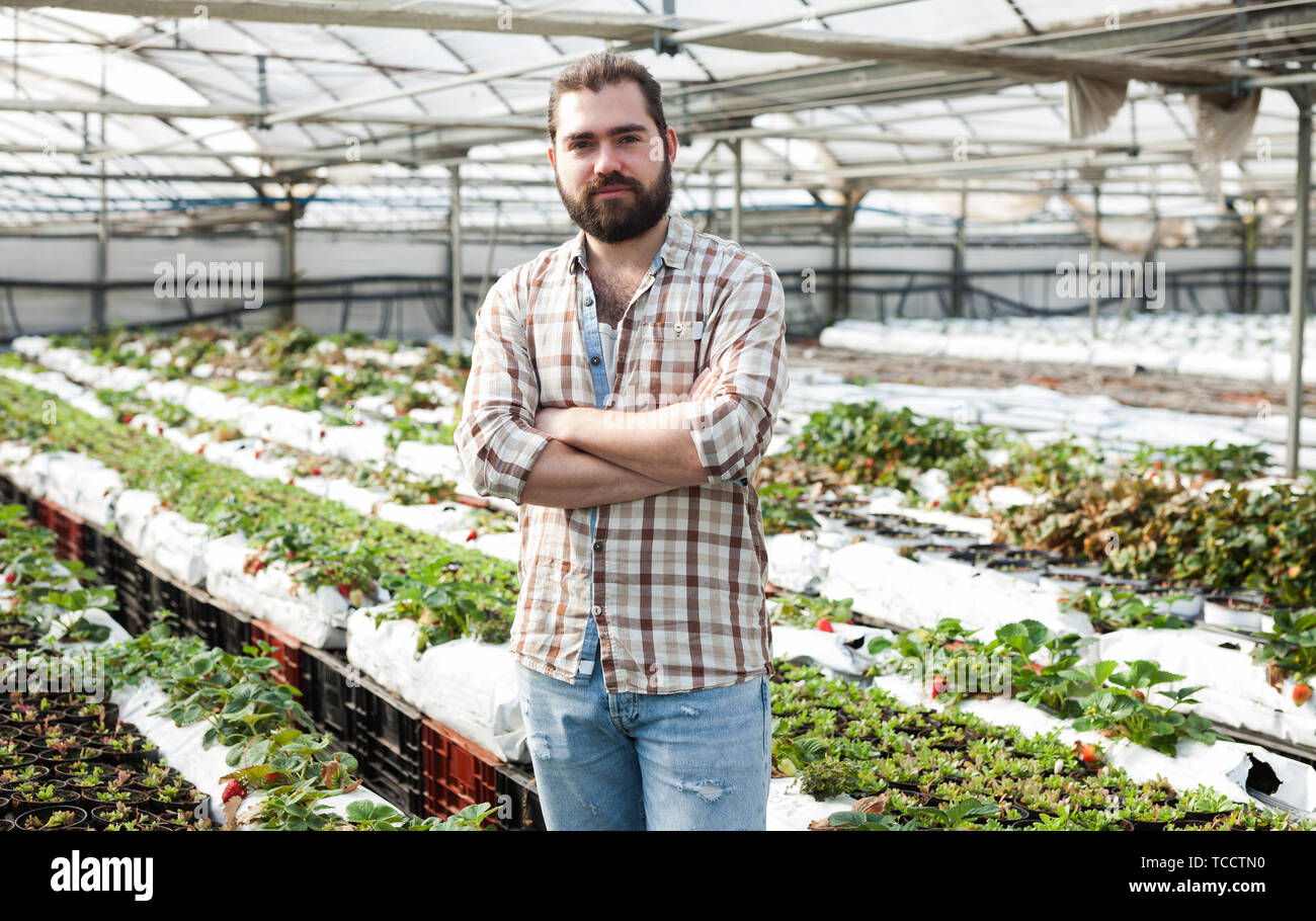 Confident young bearded farmer standing with arms crossed in his ...