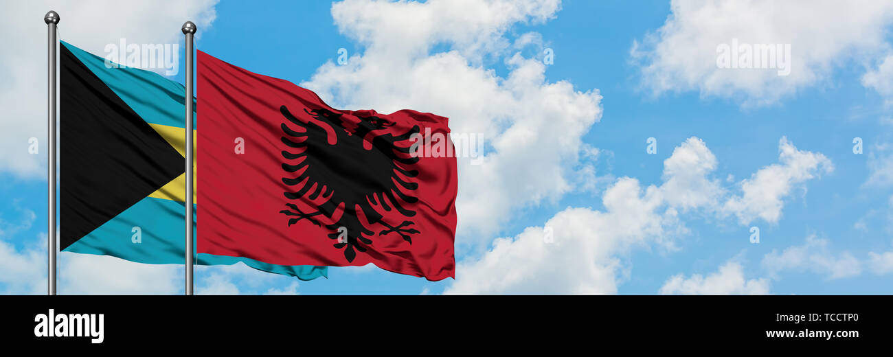 Bahamas and Albania flag waving in the wind against white cloudy blue ...