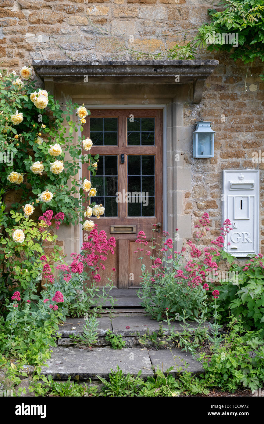 Cotswold cottage front door with yellow roses in Adlestrop village in