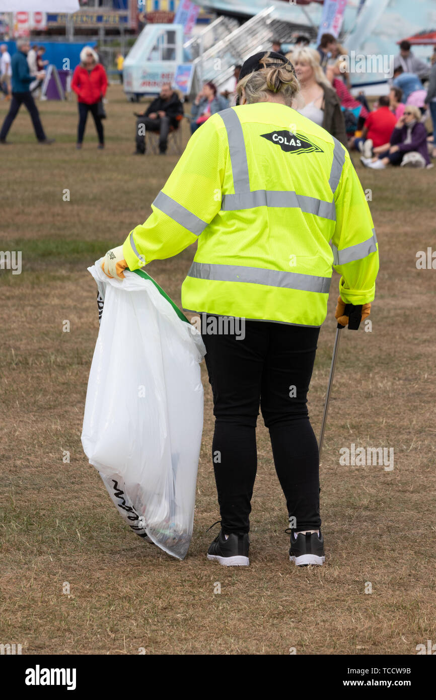 A litter picker in high visibility clothing picking up litter at a