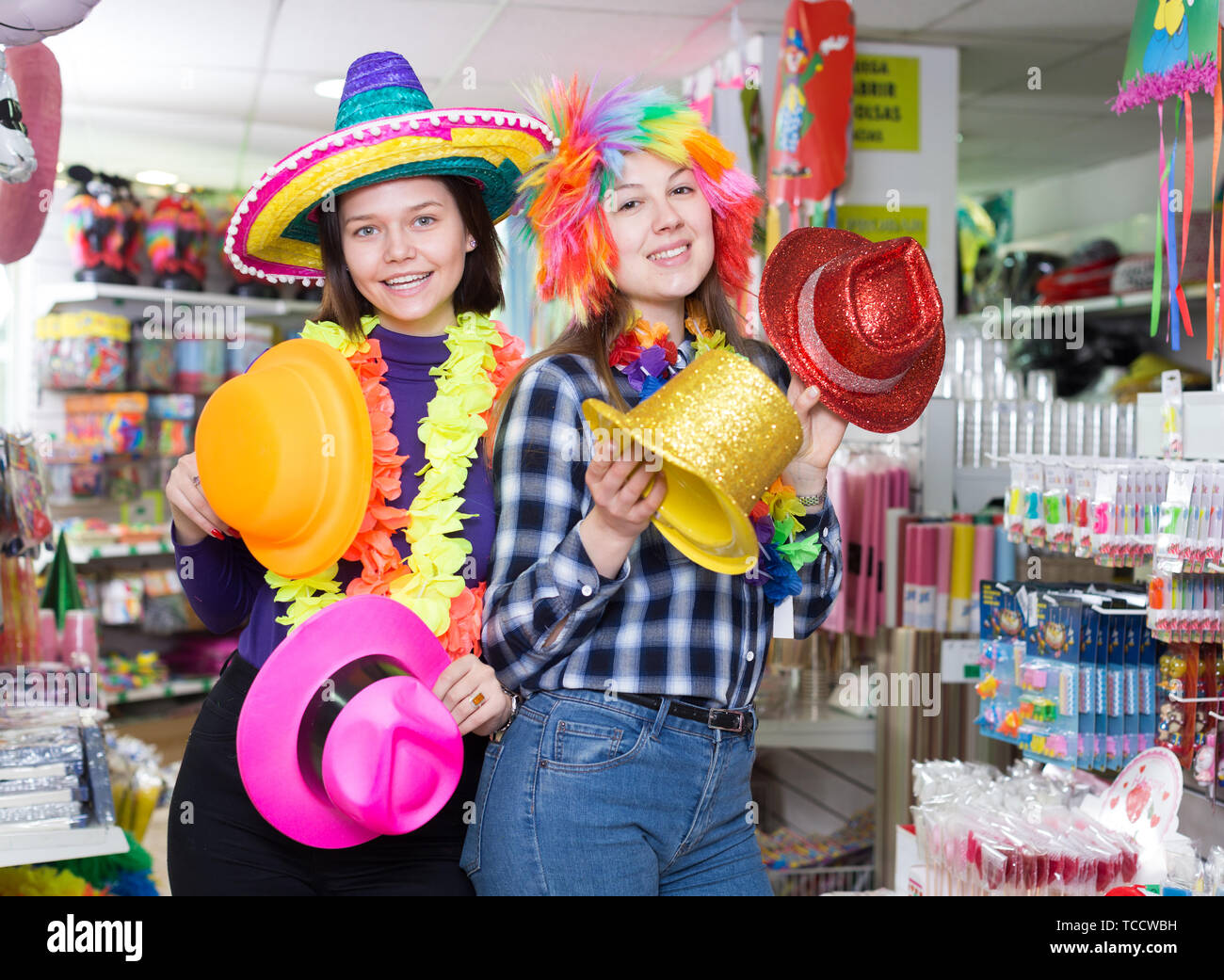 Smiling girls shopping together, looking for funny hats in store of festival  outfits and accessories Stock Photo - Alamy