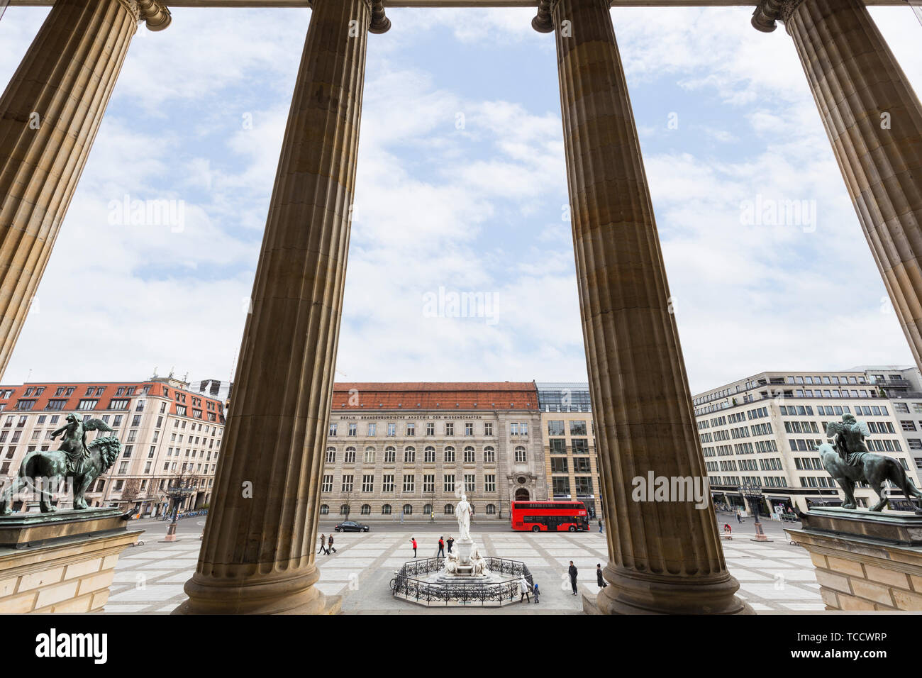 Few people at the Gendarmenmarkt Square viewed through columns in front of the Konzerthaus Berlin (Berlin Concert Hall) in Berlin, Germany, at day. Stock Photo