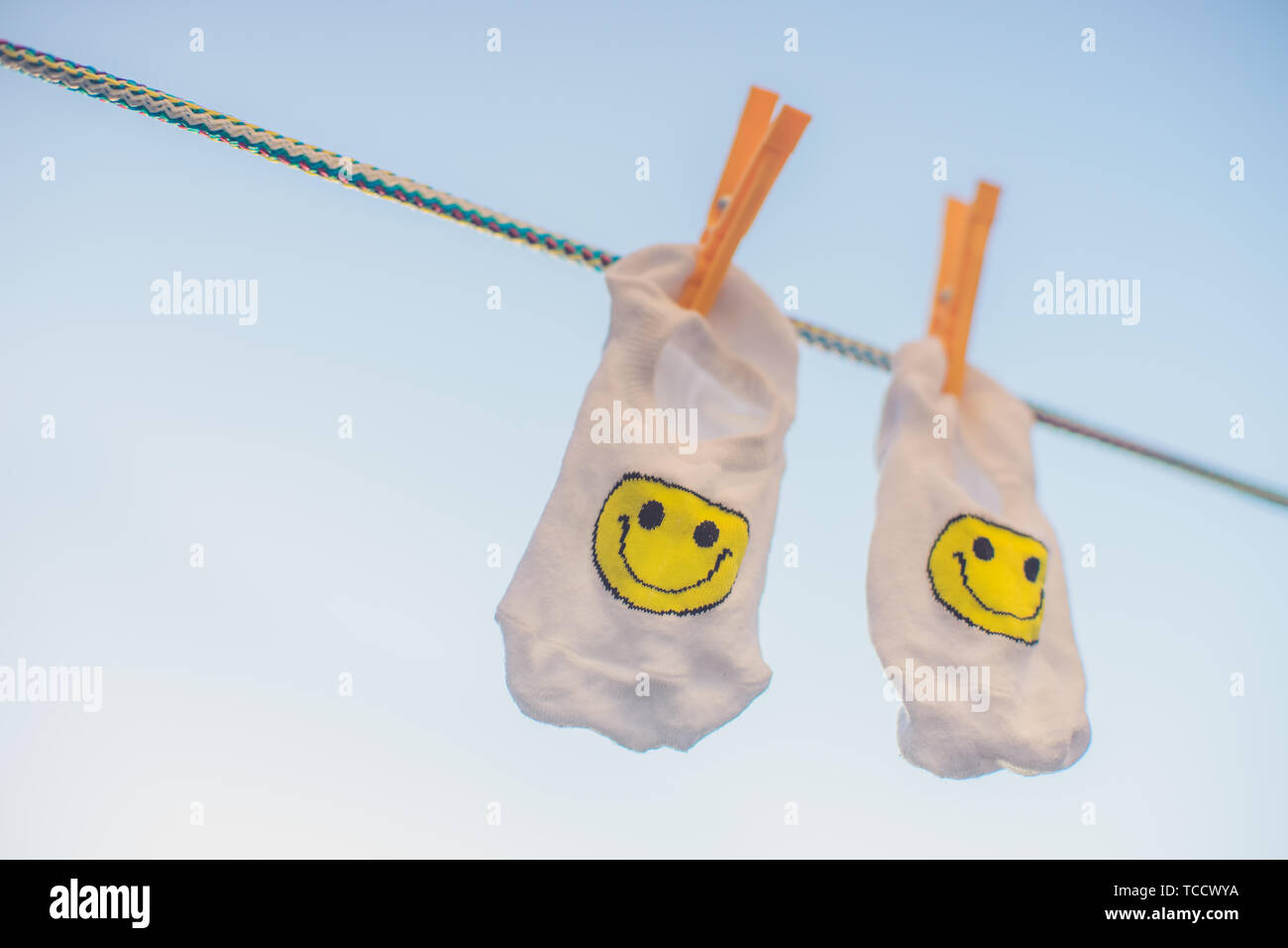 White socks with a yellow smiley emoticon hang on a rope with ...