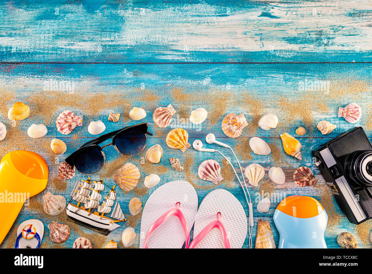 Beach accessories retro film camera sunglasses flip flop and sea shell on wooden. Top view of beach accessories on blue plank summer holiday banner tr Stock Photo