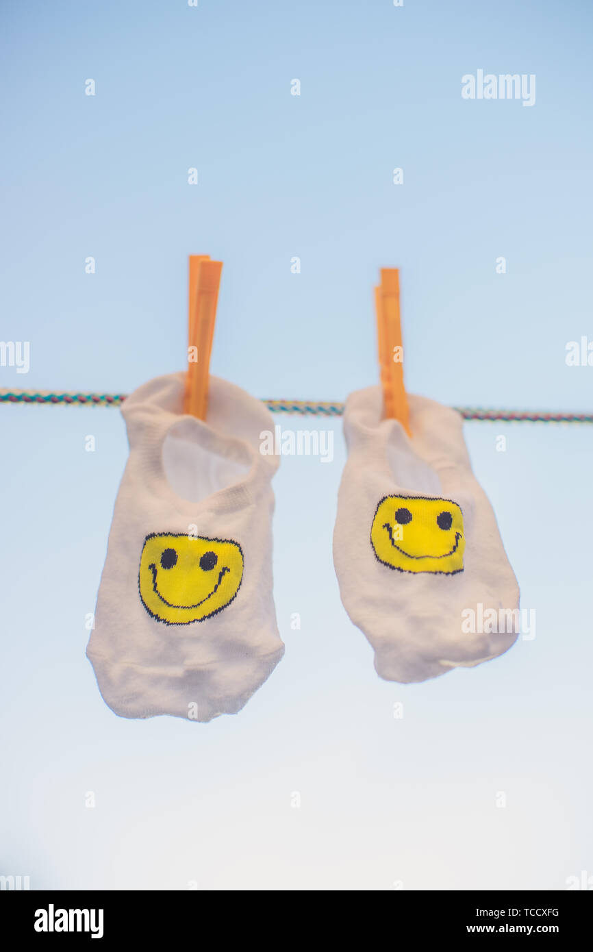 White socks with a yellow smiley emoticon hang on a rope with ...