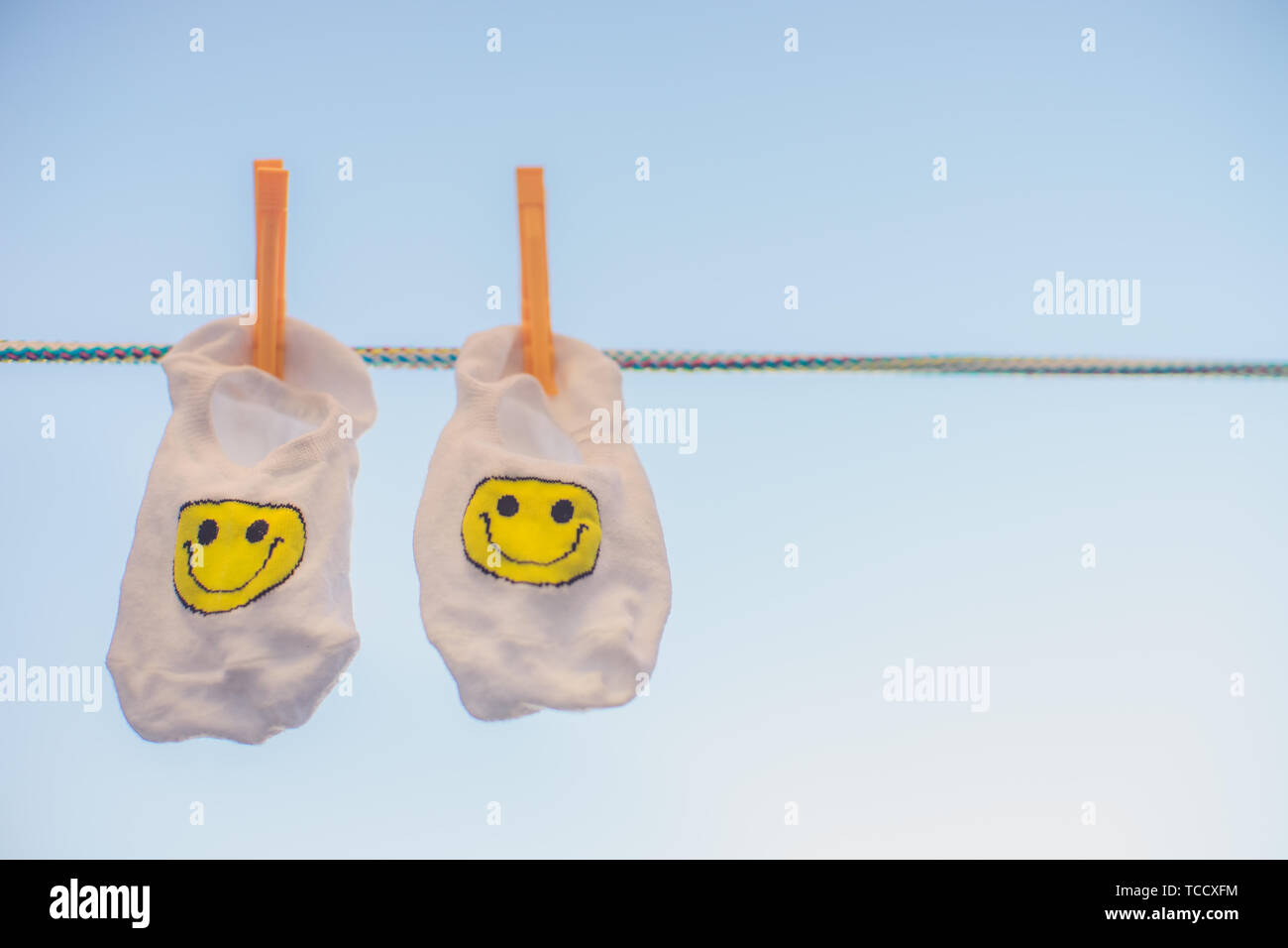 White socks with a yellow smiley emoticon hang on a rope with ...