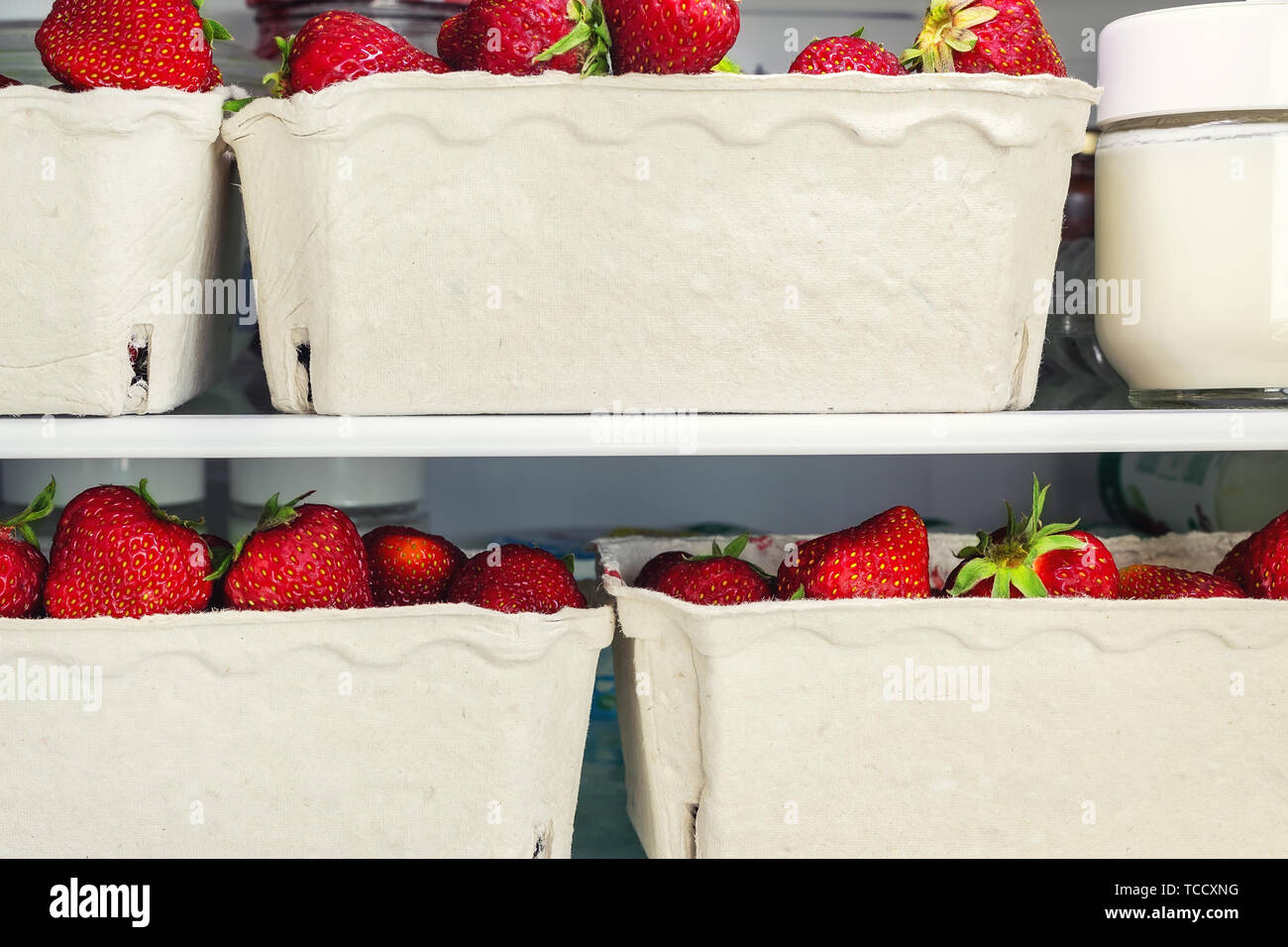 Refrigerator shelf with organic juicy strawberries in bio recycled paper boxes and homemade