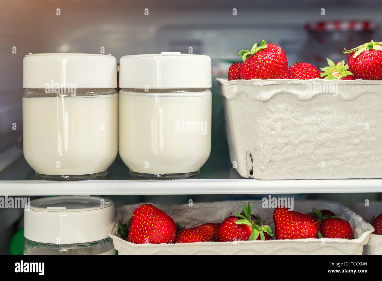 Refrigerator shelf with organic juicy strawberries in bio recycled paper boxes and homemade