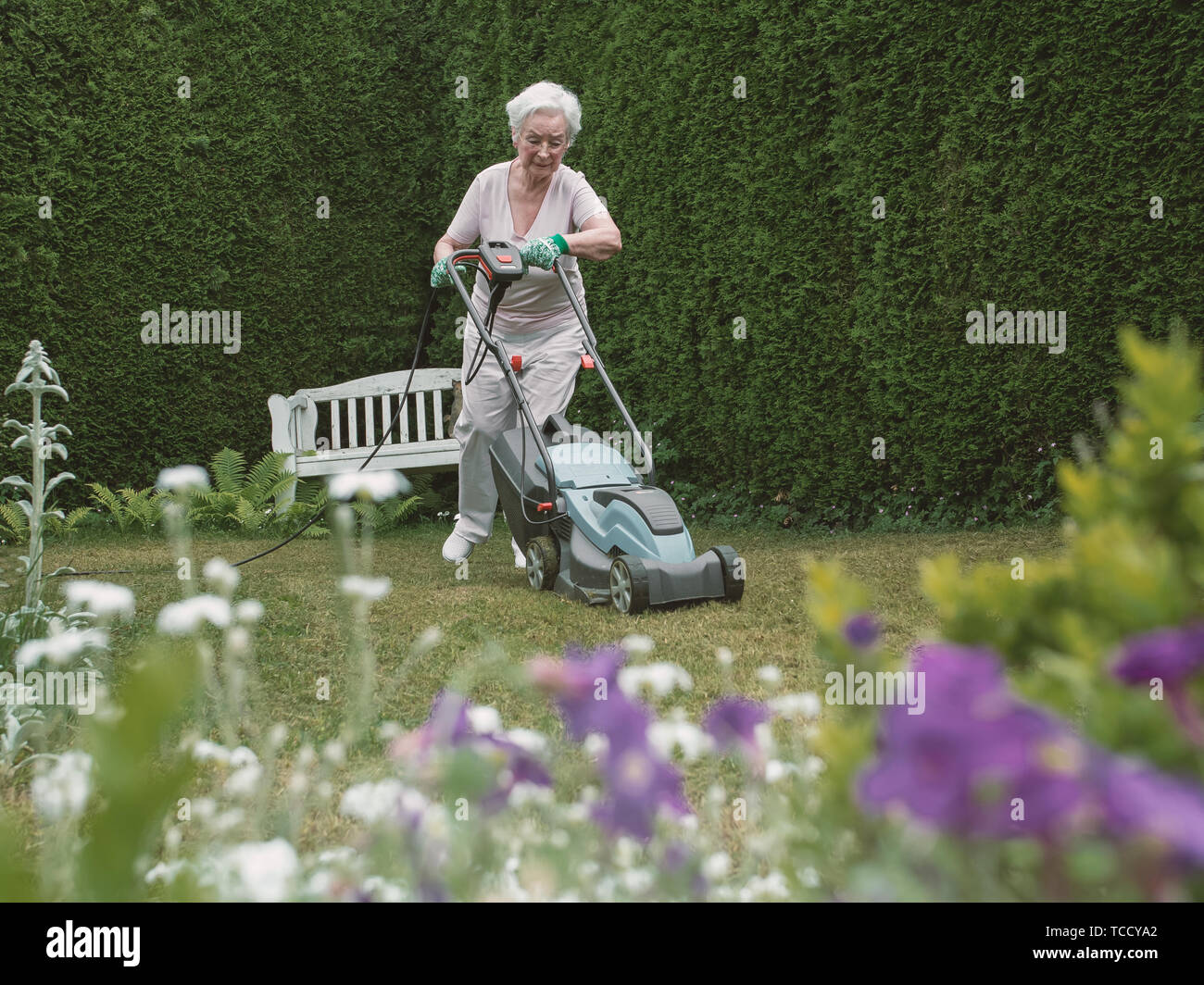 Senior woman working in the garden with mower Stock Photo