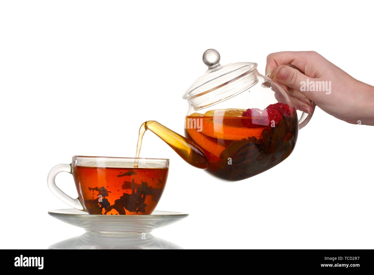 Glass teapot pouring black tea into cup isolated on white Stock Photo