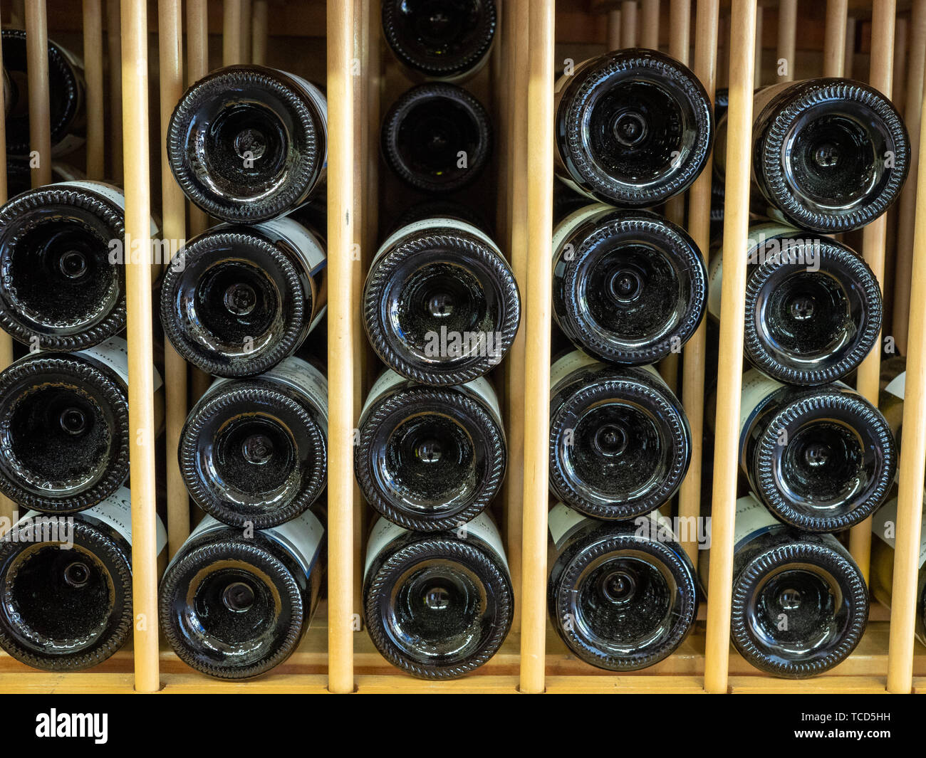 Bottles of red wine in layers in wine rack with ends with bottoms shown
