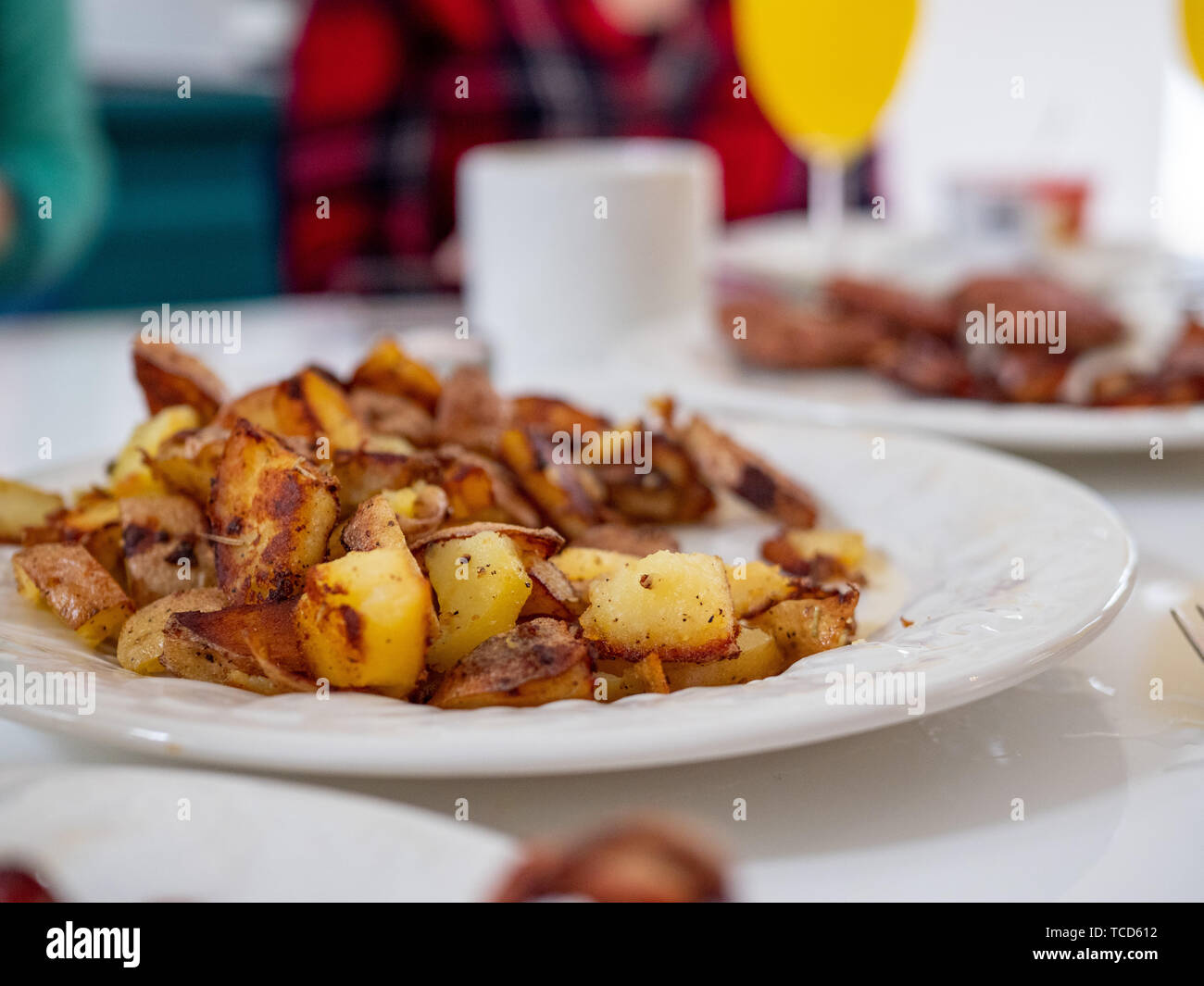Close up of traditional American breakfast plate of potatoes, sausage, bacon on a dining table with full breakfast spread Stock Photo