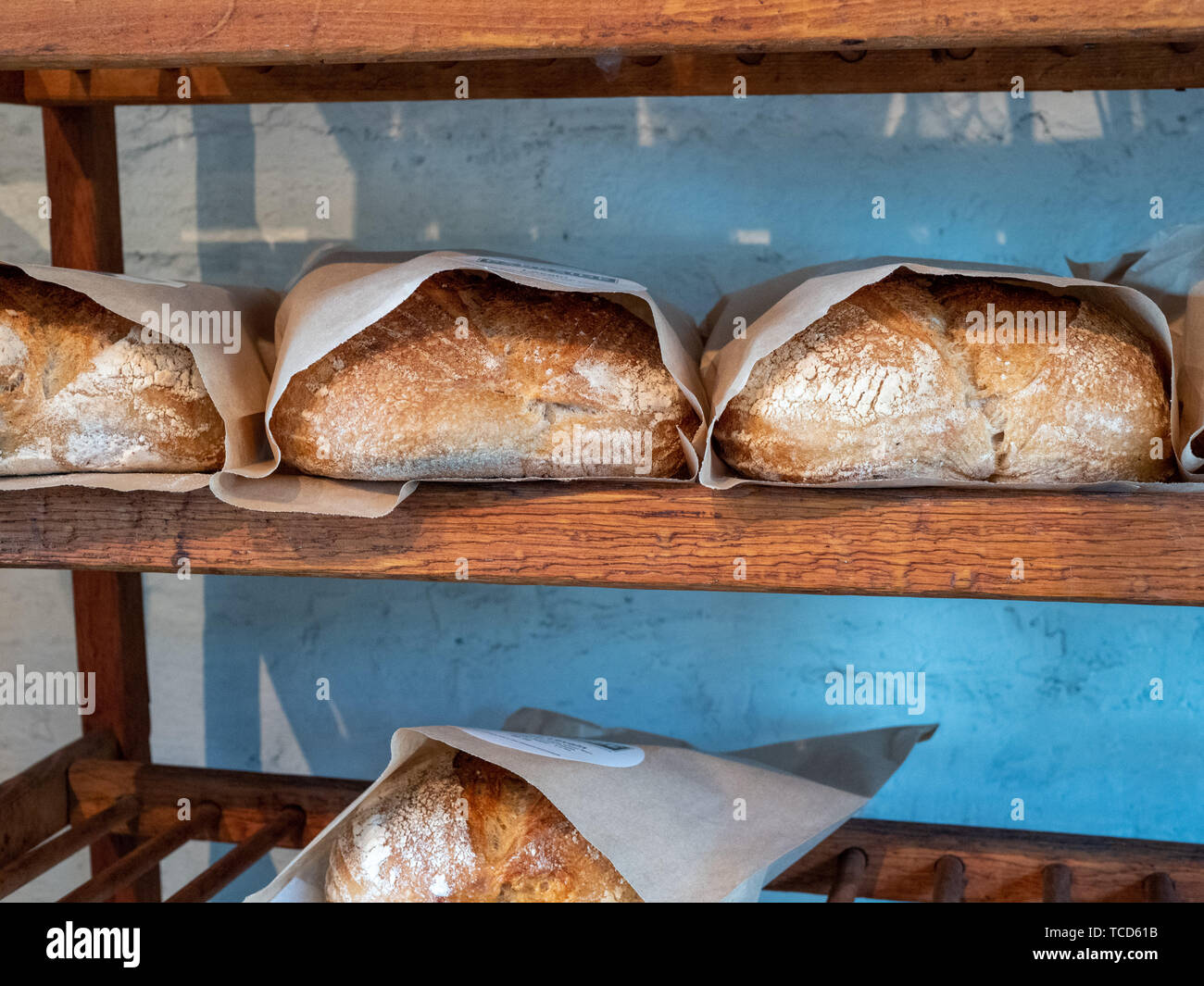 Shelf holding rows of baked and packaged loaves of bread in a bakery