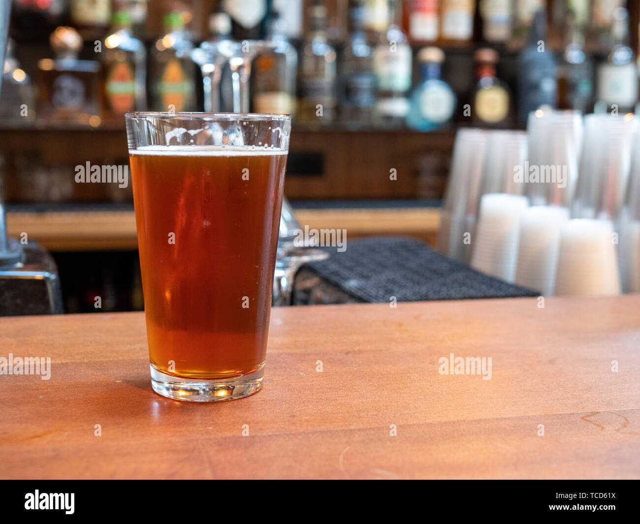 Pint glass of beer sitting on bar counter in the day time Stock Photo