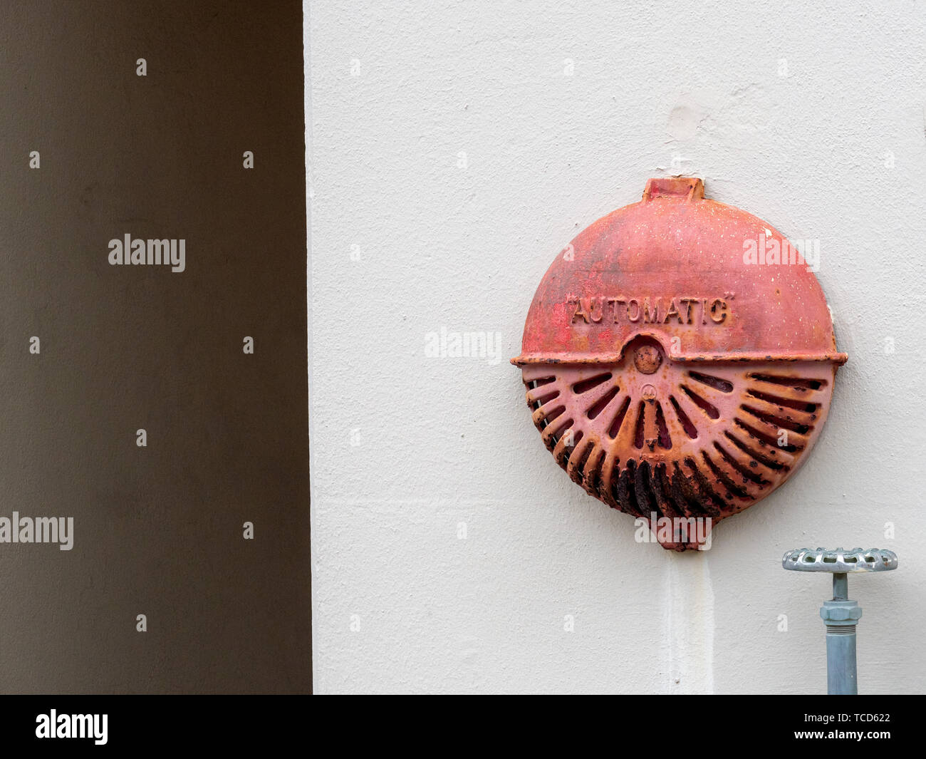 Automatic rusty old fire alarm bell hanging outside of industrial building Stock Photo