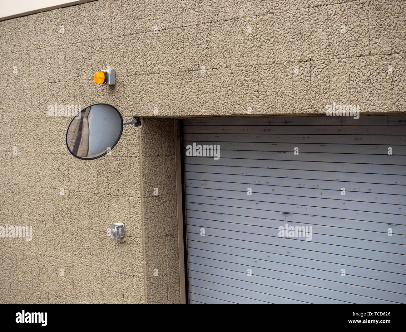 Safety mirror on corner of parking garage complex building entrance Stock Photo