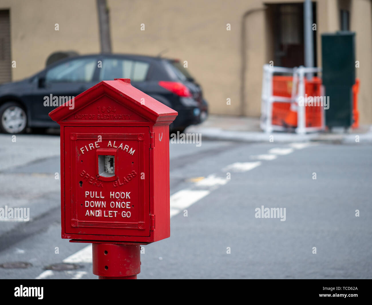 Weathered, old red fire alarm call box on street corner outside  Stock Photo