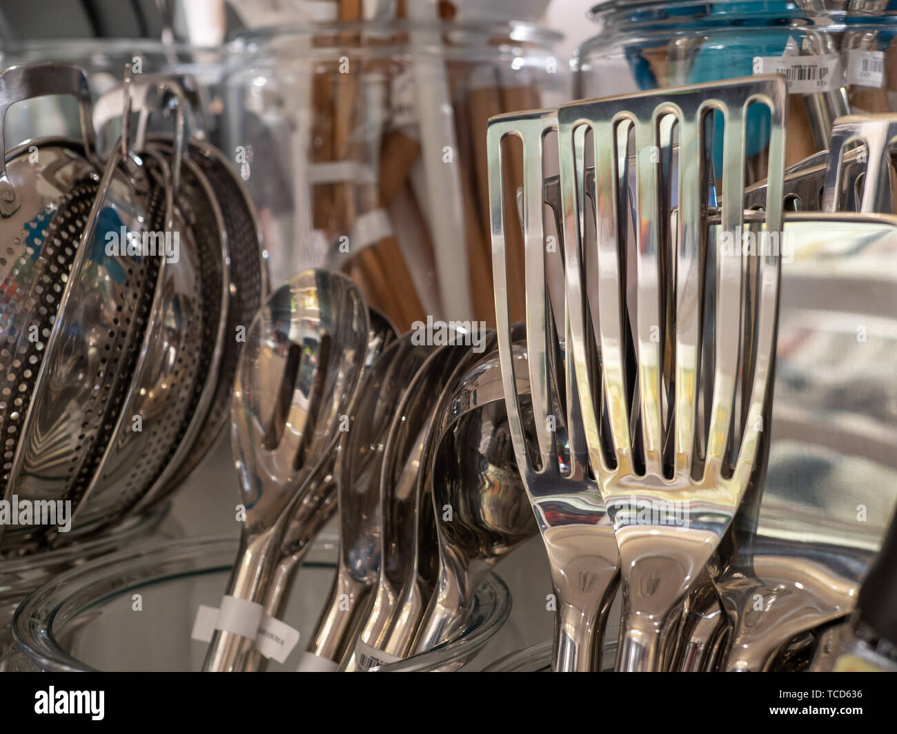 Chrome, metal fish spatula on display on rack with other utensils Stock Photo